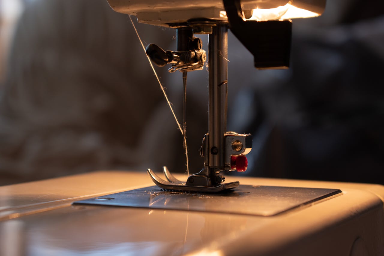 Detailed close-up of a sewing machine needle with thread, perfect for textile or craft themes.