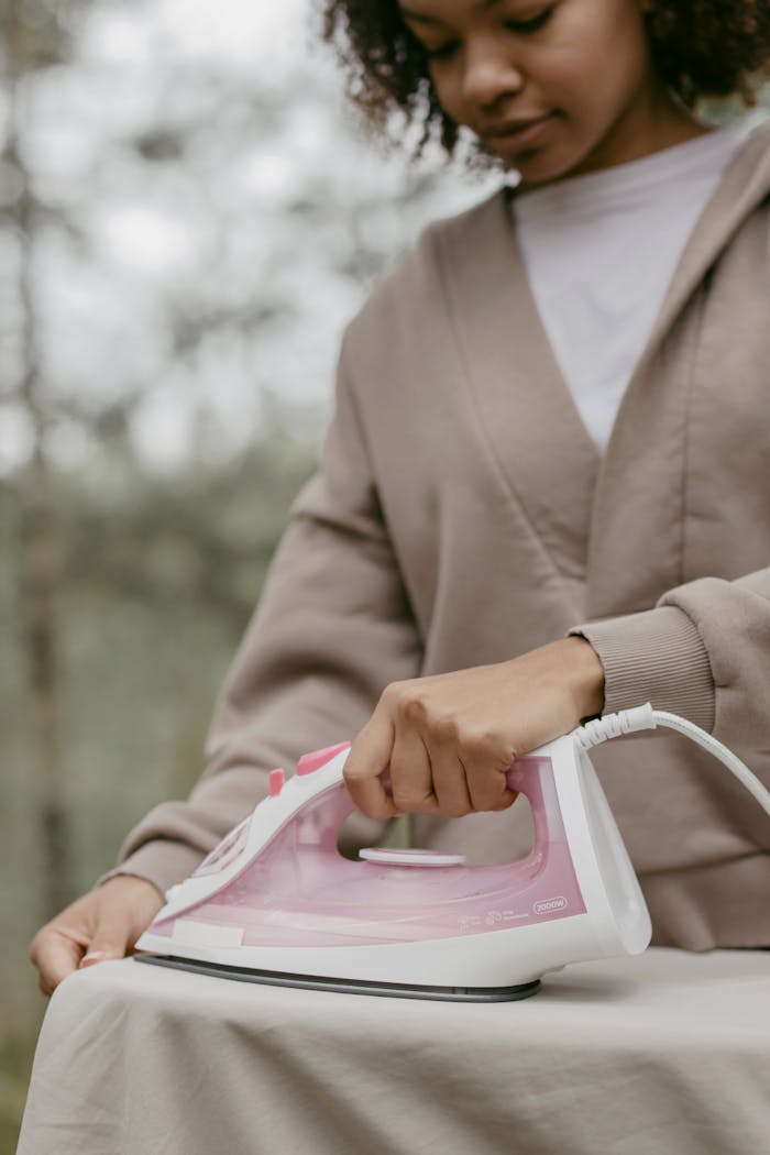 A young woman ironing clothes outdoors, combining chores with nature.
